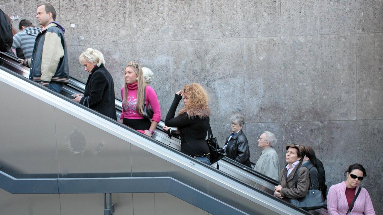 Menschen stehen und warten auf einer Rolltreppe am Stachus in München.