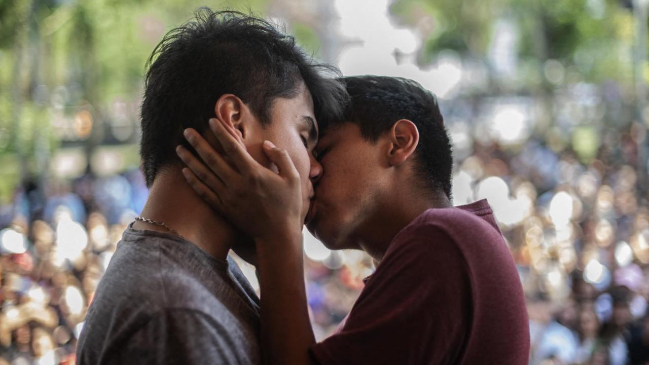 Zwei Männer küssen sich während eines Kussmarathons vor Publikum.
