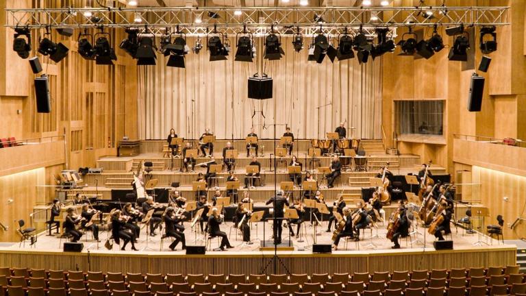 Ein nicht all zu groß besetztes Orchester spielt auf der Bühne mit Dirigenten. Ein nicht all zu groß besetztes Orchester spielt auf der Bühne mit Dirigenten.