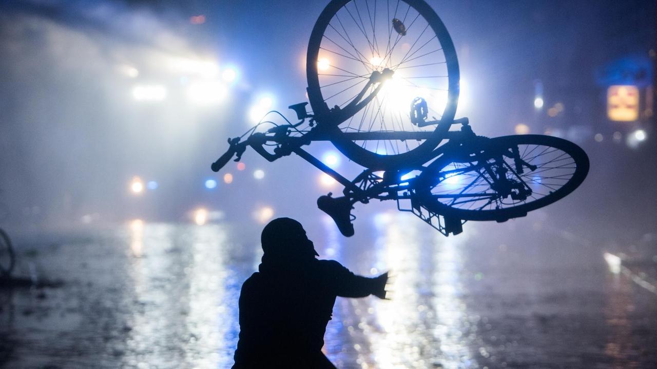 Ein Randalierer wirft im Schanzenviertel ein Fahrrad in Richtung von Wasserwerfern. Ein Randalierer wirft im Schanzenviertel ein Fahrrad in Richtung von Wasserwerfern.