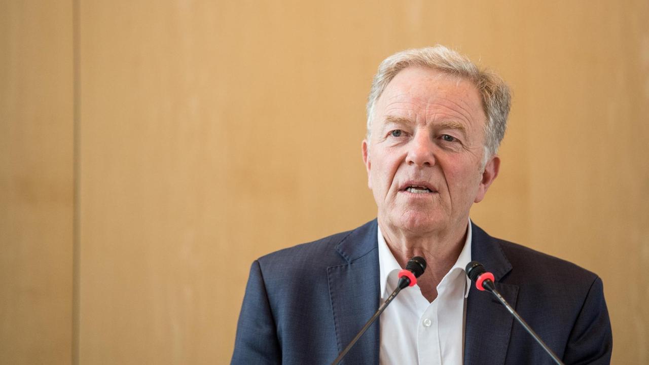 Martin Schairer spricht in zwei Mikrofonen vor einem beigen Hintergrund. Martin Schairer spricht in zwei Mikrofonen vor einem beigen Hintergrund.