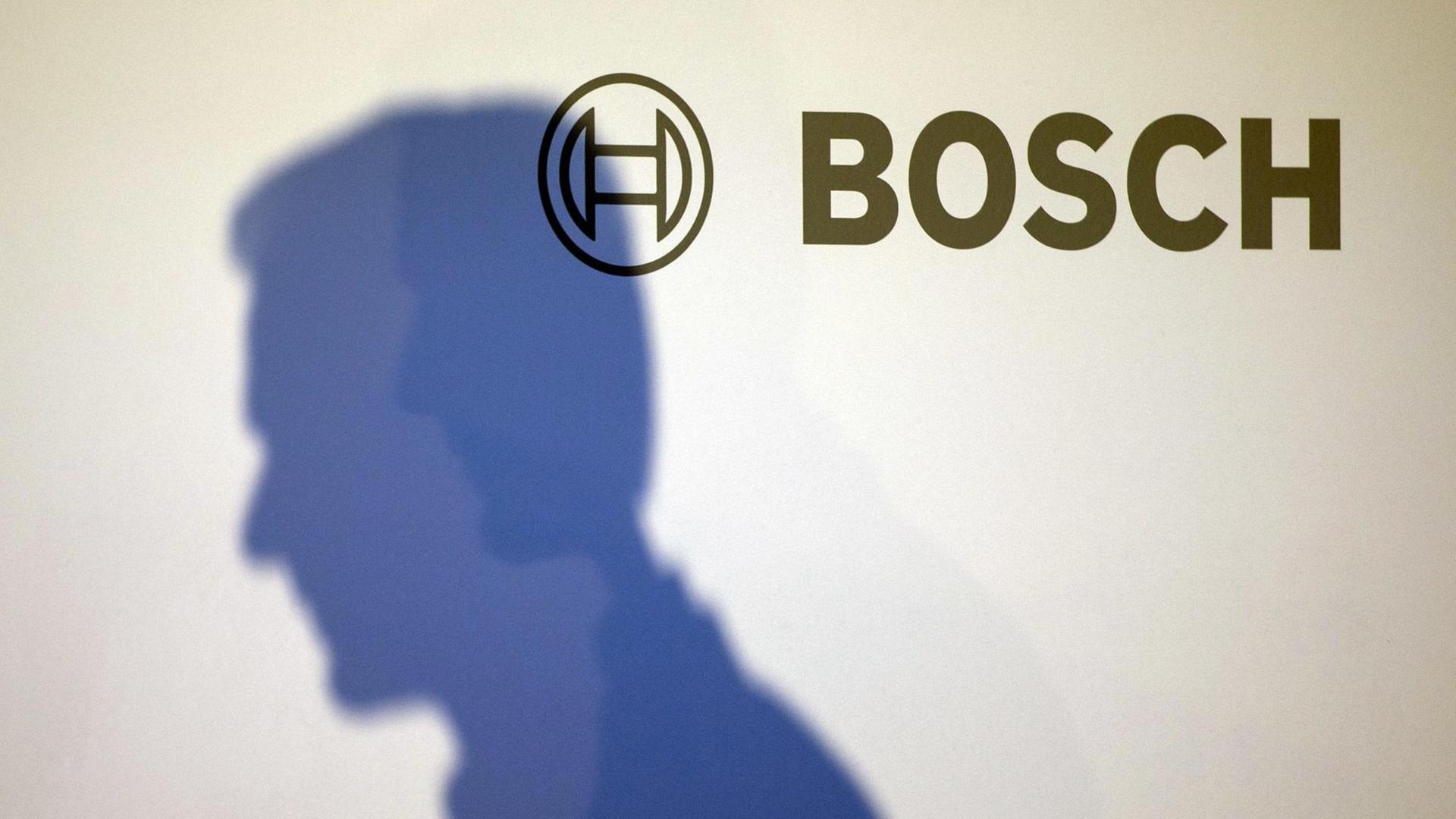 Der Schatten des Vorsitzenden von Bosch, Volkmar Denner, auf einer weißen Wand mit Bosch-Logo. Der Schatten des Vorsitzenden von Bosch, Volkmar Denner, auf einer weißen Wand mit Bosch-Logo.
