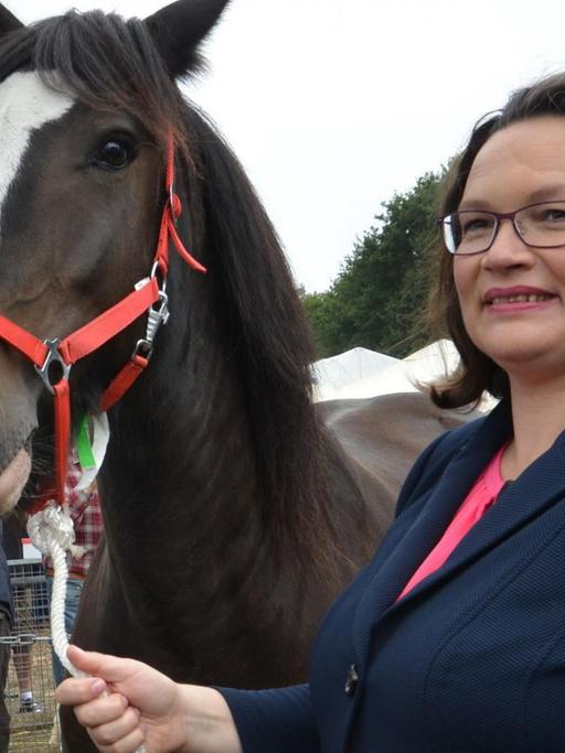 Andrea Nahles, SPD-Parteivorsitzende, besucht einen Pferdemarkt, der während des Stoppelmarktes abgehalten wird und steht dabei neben einem Pferd.