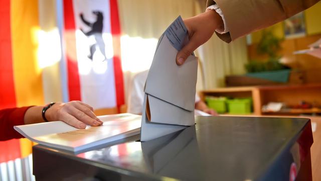 Eine Wählerin steckt ihren Stimmzettel in Berlin in die Wahlurne.