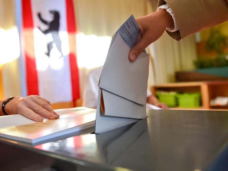 Eine Wählerin steckt ihren Stimmzettel in Berlin in die Wahlurne.