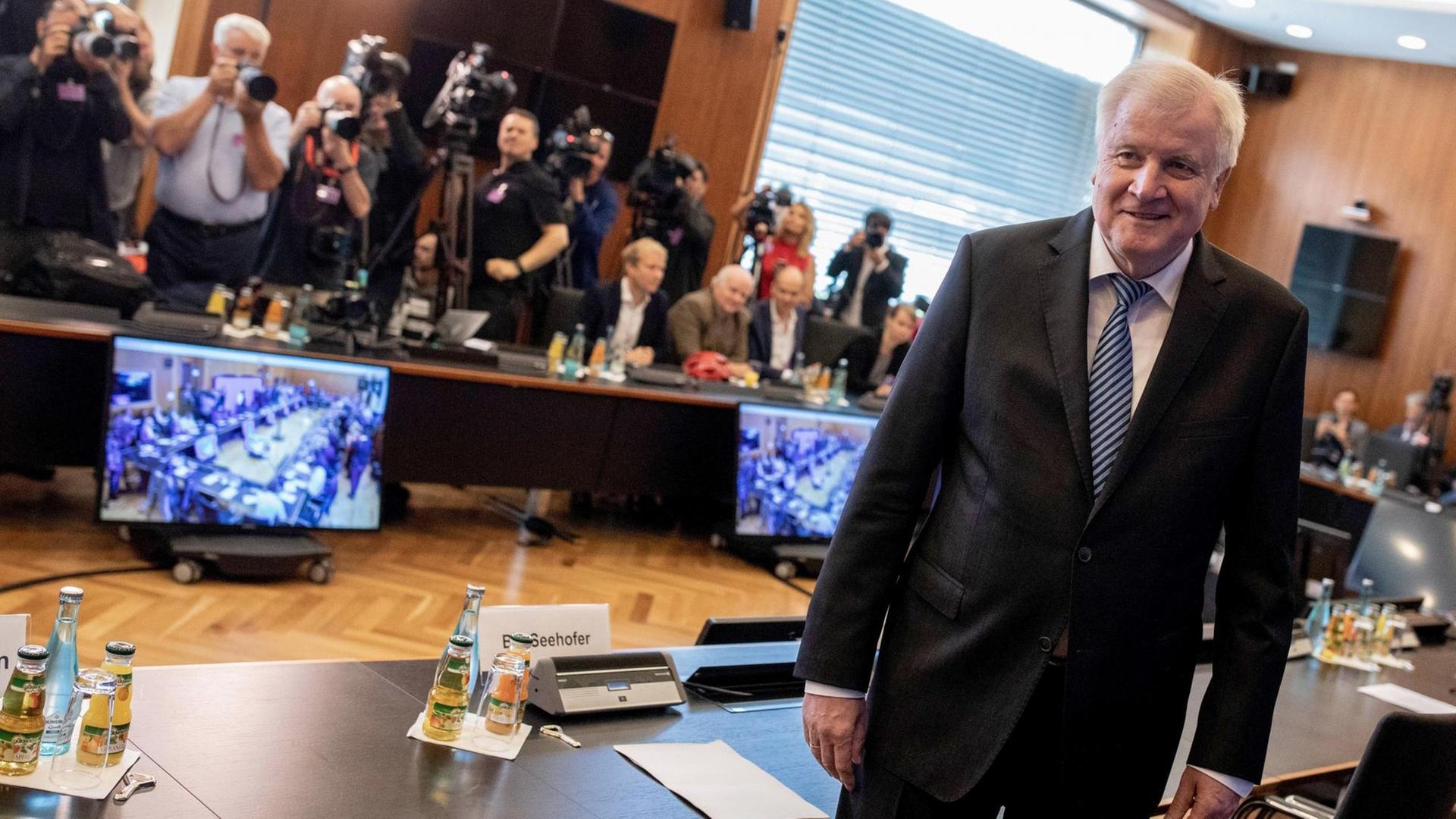 Seehofer steht an einem Tisch, im Hintergrund mehrere Fotojournalisten, auf dem Boden Computer. Seehofer steht an einem Tisch, im Hintergrund mehrere Fotojournalisten, auf dem Boden Computer.