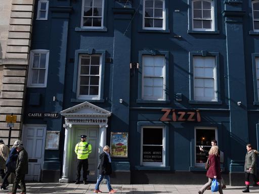 A poice officer stands guard outside a branch of the Italian chain restaurant Zizzi close to The Maltings shopping centre in Salisbury, southern England, on March 6, 2018 which was closed in connection to the ongoing major incident sparked after a man and a woman were found critically ill on a bench at the shopping centre on March 4. British police raced Tuesday to identify an unknown substance that left a former Russian double agent fighting for his life, in what a senior lawmaker said bore the hallmarks of a Russian attack. Moscow said it had no information about the "tragic" collapse of the man, identified by the media as Sergei Skripal, in the quiet southern English city of Salisbury on Sunday, but said it would be happy to cooperate if requested by British authorities. Specialist officers from the counter-terrorism squad are helping investigate the incident, which also left a 33-year-old woman -- reported to be Skripal's daughter Yulia -- in a critical condition in what is feared to be a poison plot. / AFP PHOTO / Chris J Ratcliffe