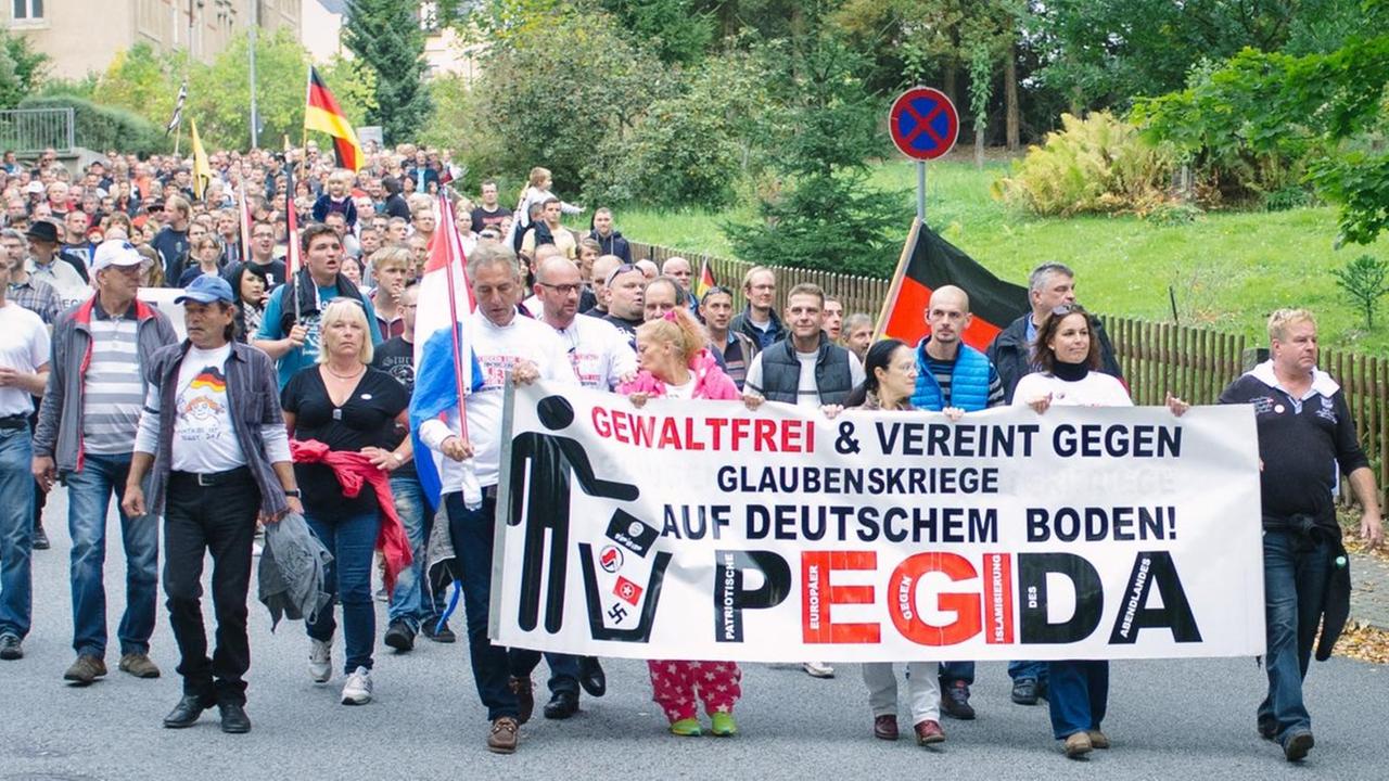 Demonstranten mit einem Pegida-Banner laufen durch Sebnitz.