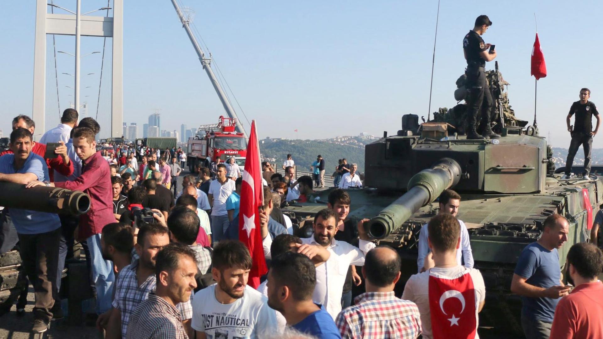 Polizisten und Erdogan-Anhänger scharen sich um einen Panzer vor der Bosporusbrücke in Istanbul. Polizisten und Erdogan-Anhänger scharen sich um einen Panzer vor der Bosporusbrücke in Istanbul.