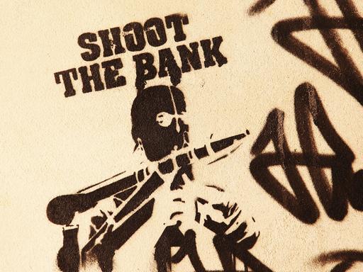 Ein gesprühtes "Stencil" zeigt die Worte "Shoot the Bank" und einen Mann mit Maske und einer Panzerfaust, aufgenommen 2012 in Berlin im Bezirk Mitte