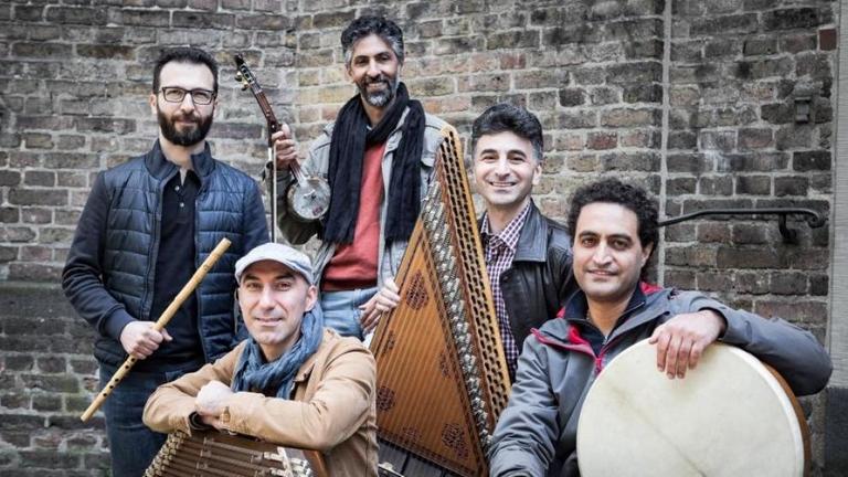 Die fünf Musiker sitzen und stehen mit ihren orientalischen Instrumenten vor einer Mauer Die fünf Musiker sitzen und stehen mit ihren orientalischen Instrumenten vor einer Mauer