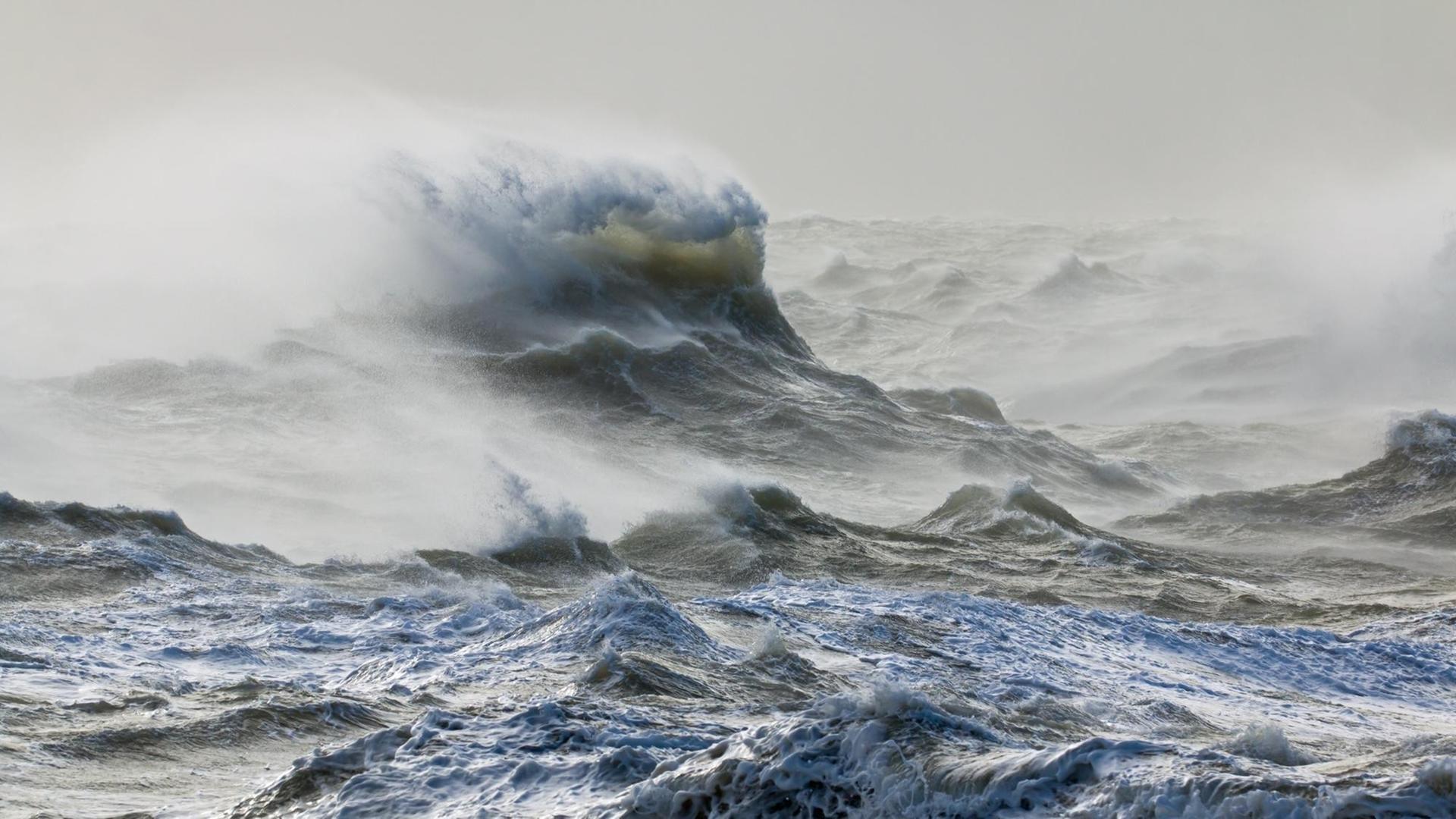 Aufgewühlte graue Wellen und stürmische See bei Newhaven, East Sussex.