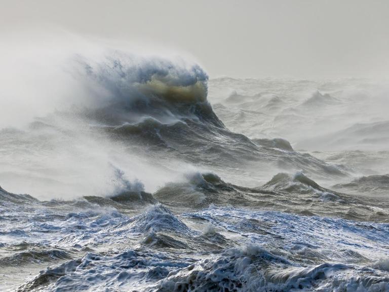 Aufgewühlte graue Wellen und stürmische See bei Newhaven, East Sussex.