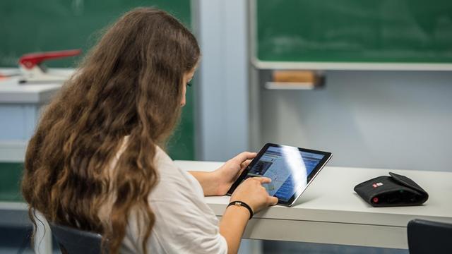 Eine Schülerin arbeitet einem Klassenzimmer an einem Tabletcomputer.