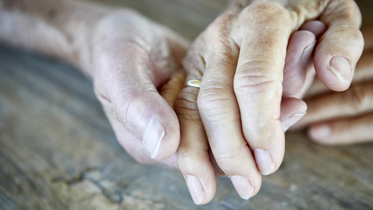 Die Hände zweier älterer Menschen liegen ineinander.