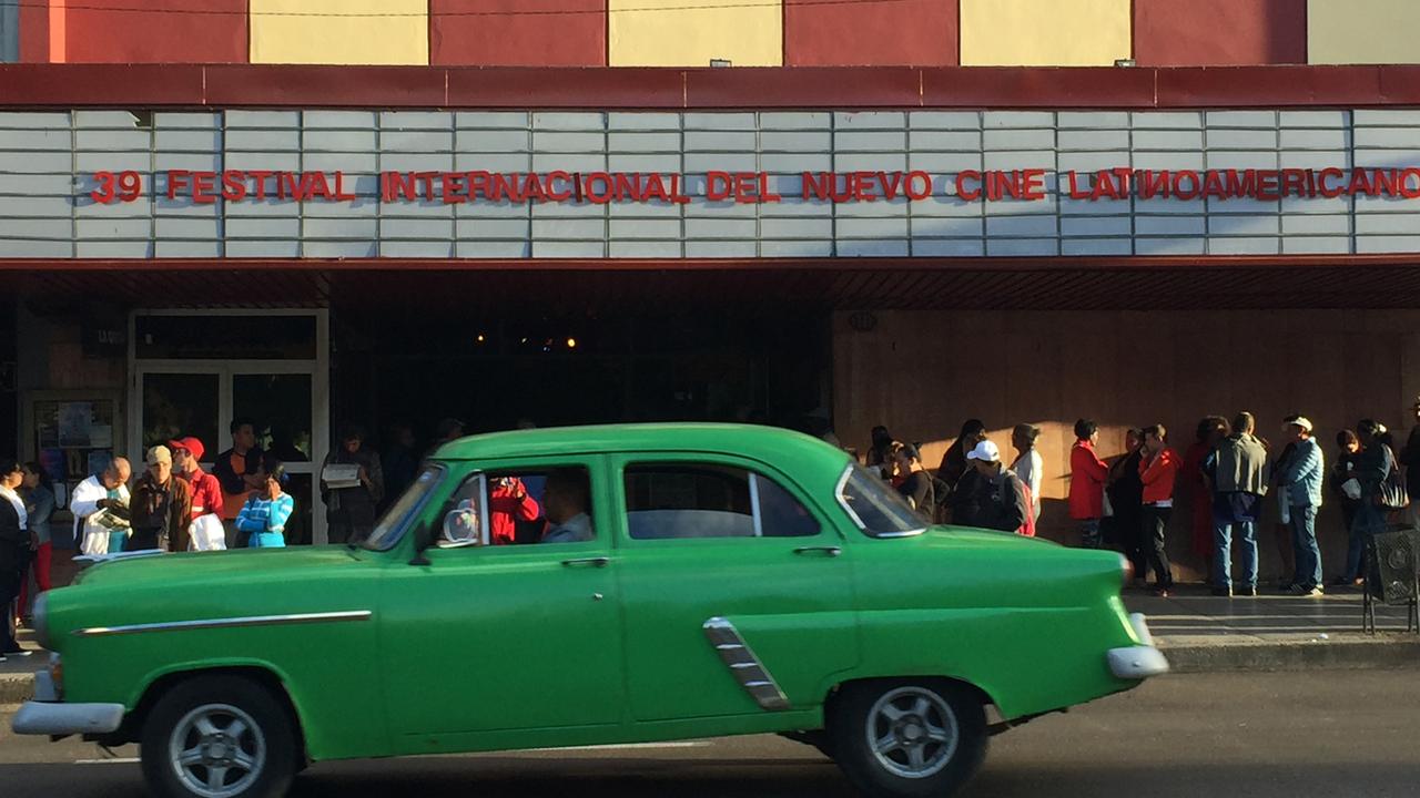Vor einem Kino in der kubanischen Hauptstadt Havanna fährt ein alter grüner Straßenkreuzer. Vor einem Kino in der kubanischen Hauptstadt Havanna fährt ein alter grüner Straßenkreuzer.