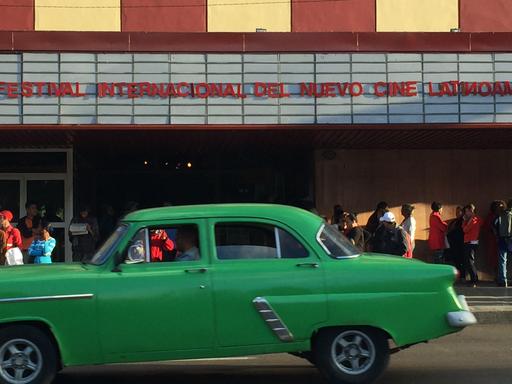 Vor einem Kino in der kubanischen Hauptstadt Havanna fährt ein alter grüner Straßenkreuzer.