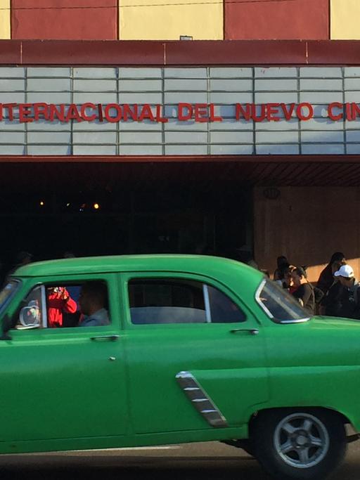 Vor einem Kino in der kubanischen Hauptstadt Havanna fährt ein alter grüner Straßenkreuzer.