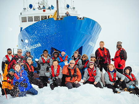 Die Passagiere der "Akademik Shokalskiy" vor dem Bug des Schiffes im Polarmeer.