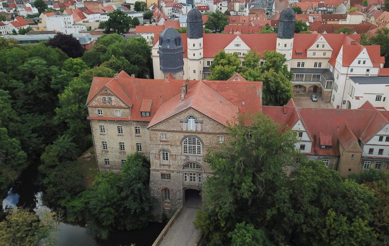 Luftbild vom Schlossensemble in Köthen, das von hohen Bäumen umgeben ist. Luftbild vom Schlossensemble in Köthen, das von hohen Bäumen umgeben ist.
