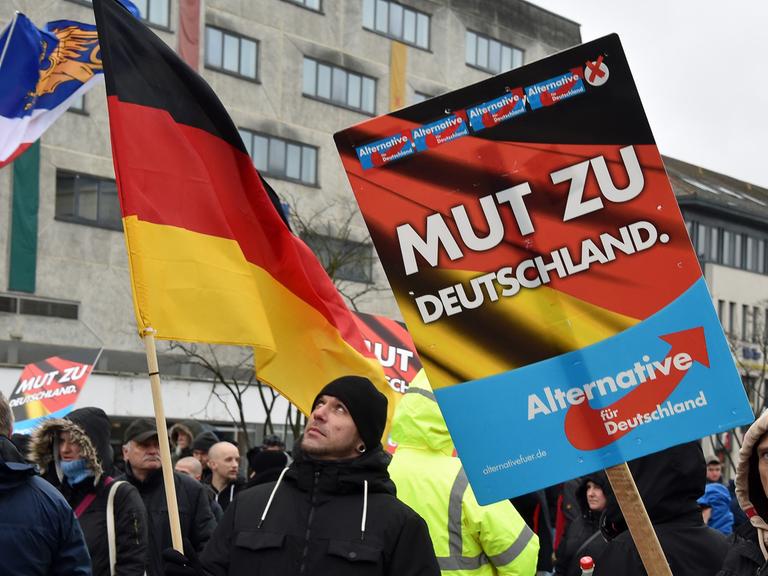 Mit Plakaten und Fahnen stehen AfD-Anhänger am 30. Januar 2016 in Neubrandenburg / Mecklenburg-Vorpommern auf dem Marktplatz.