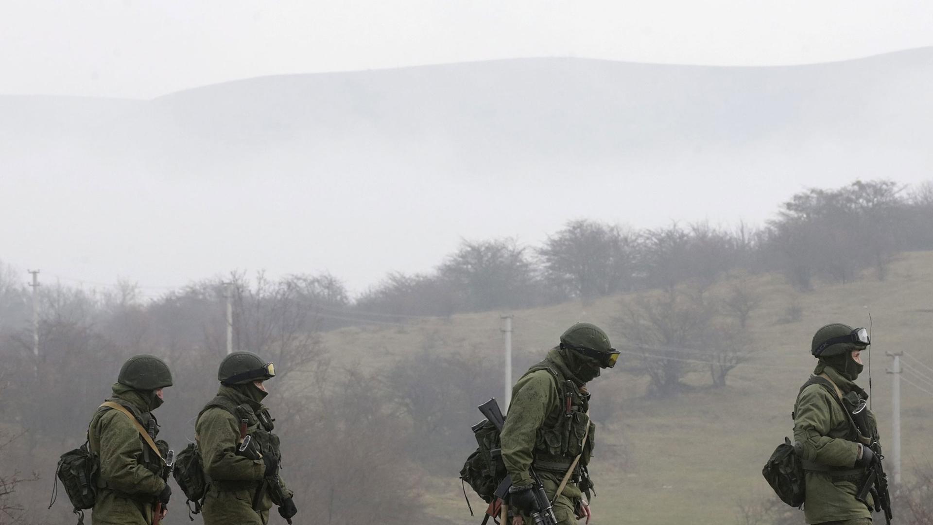 Vier bewaffnete Männer in Militäruniform gehen auf einem Weg in der Nähe der Stadt Simferopol auf der ukrainischen Halbinsel Krim. Vier bewaffnete Männer in Militäruniform gehen auf einem Weg in der Nähe der Stadt Simferopol auf der ukrainischen Halbinsel Krim.
