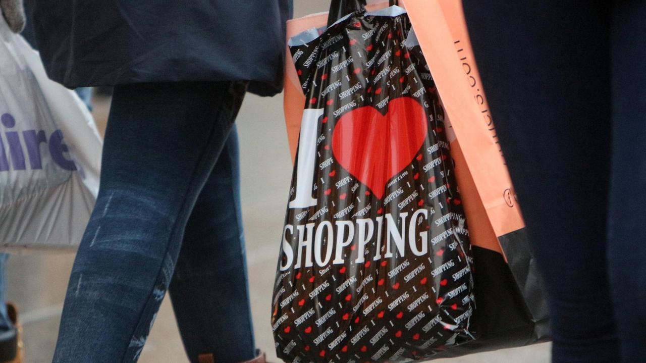 Frau trägt eine Plastiktüte mit Aufschrift "I Love Shopping" Frau trägt eine Plastiktüte mit Aufschrift "I Love Shopping"