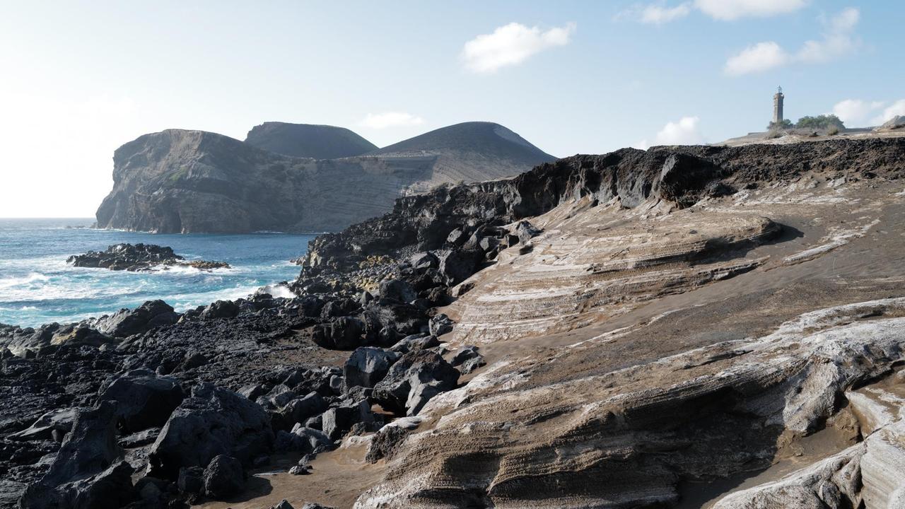 Eine schwarze hügelige Vulkanlandschaft ohne Vegetation am Meer. Eine schwarze hügelige Vulkanlandschaft ohne Vegetation am Meer.