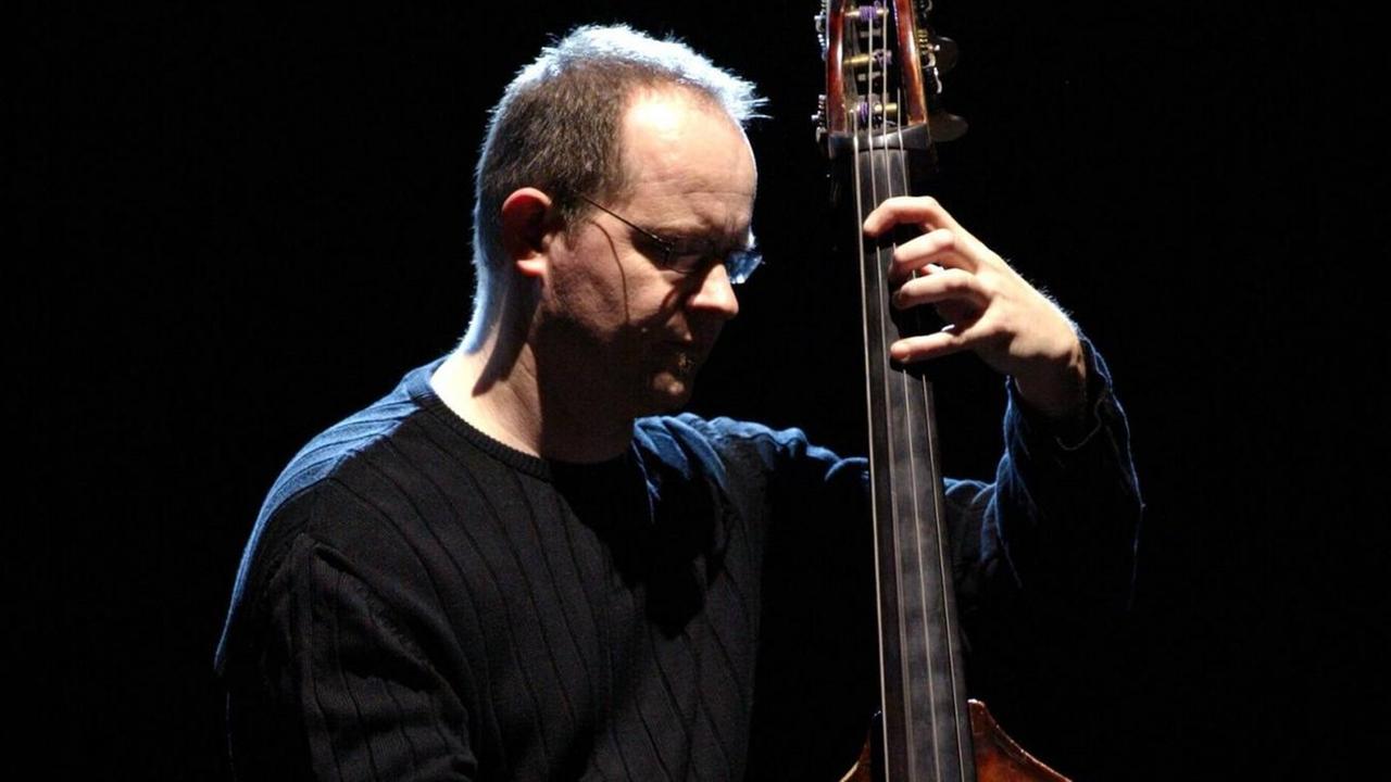 Ein Mann spielt Kontrabass vor schwarzem Hintergrund Ein Mann spielt Kontrabass vor schwarzem Hintergrund