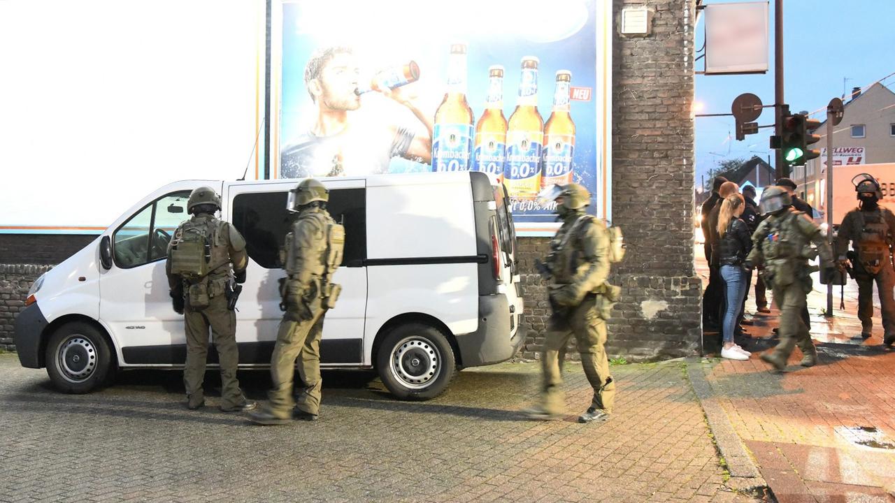 Straßenszene: Polizeibeamte in Kampfanzügen bereiten sich auf einen Einsatz gegen die Organisierte Kriminalität vor. Straßenszene: Polizeibeamte in Kampfanzügen bereiten sich auf einen Einsatz gegen die Organisierte Kriminalität vor.