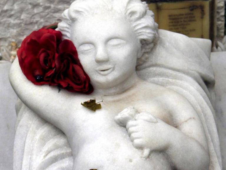 Grabplatte auf einem Kindergrab mit marmorner Engelsfigur auf einem Friedhof.