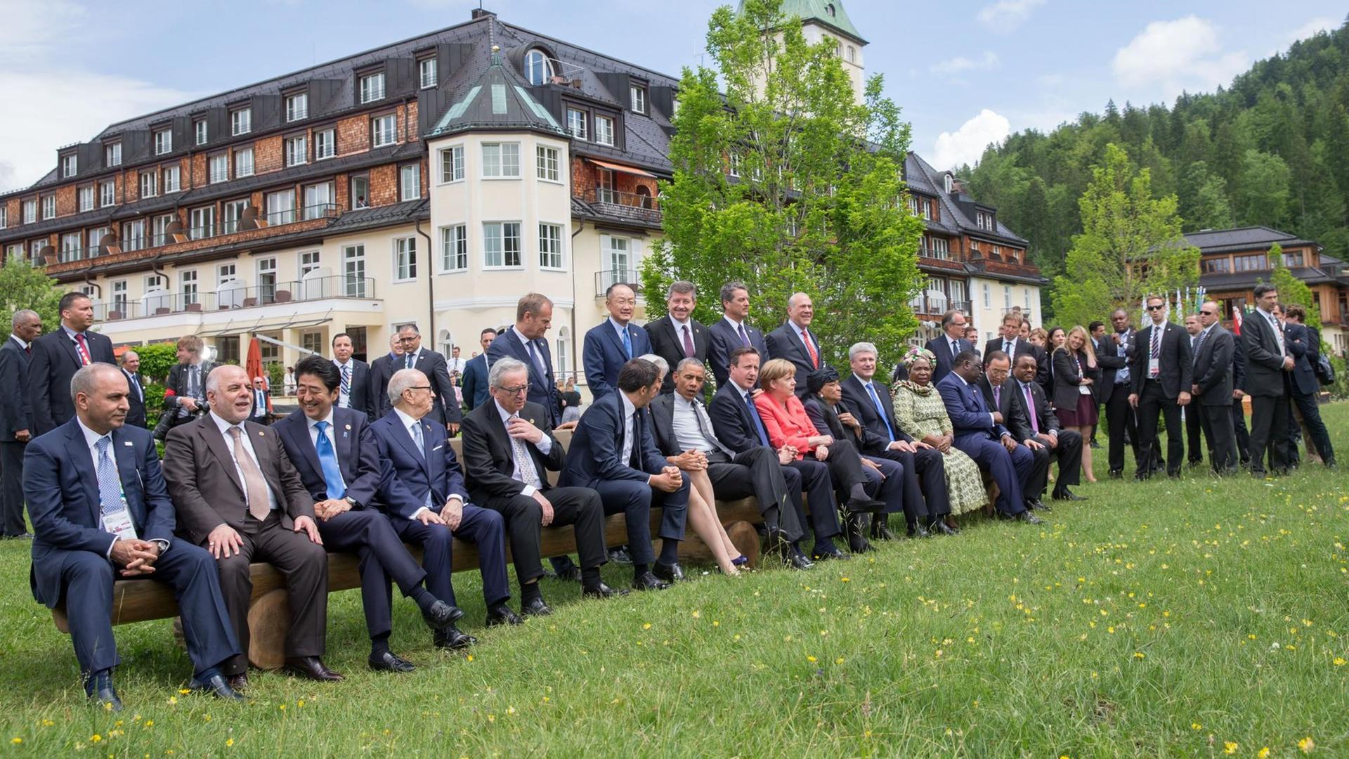 Bundeskanzlerin Angela Merkel und die Staats- und Regierungschefs von G7 und der Outreach Staaten haben sich vor Schloss Elmau auf einer Bank versammelt.