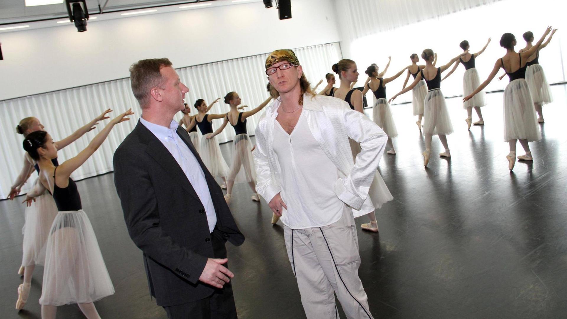 Der ehemalige Schulleiter, Prof. Dr. Ralf Stabel (li.) und der ehemalige künstlerischer Leiter, Prof Gregor Seyffert (re.), in einem Tanzsaal mit einer Gruppe Balletttänzerinnen im Hintergrund an der Staatlichen Ballettschule Berlin. Der ehemalige Schulleiter, Prof. Dr. Ralf Stabel (li.) und der ehemalige künstlerischer Leiter, Prof Gregor Seyffert (re.), in einem Tanzsaal mit einer Gruppe Balletttänzerinnen im Hintergrund an der Staatlichen Ballettschule Berlin.