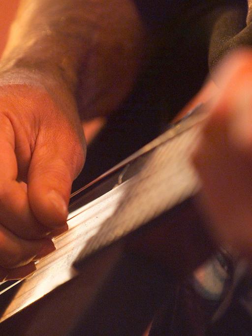 Die Hände eines Musikers beim Gitarre spielen.