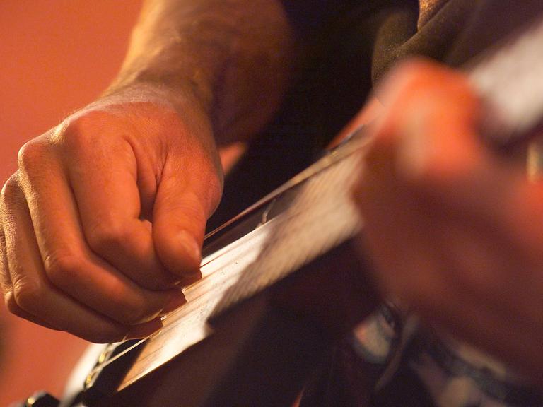 Die Hände eines Musikers beim Gitarre spielen.