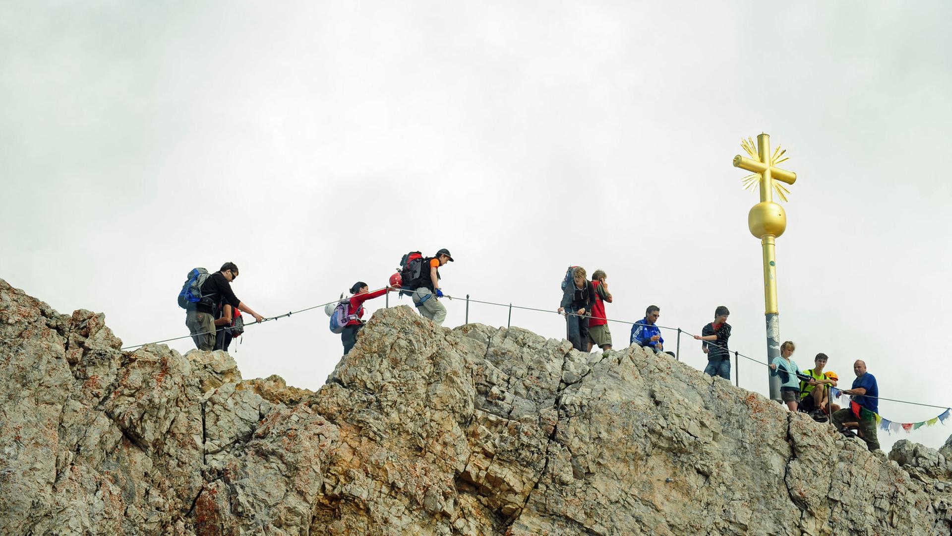 Mehrere Bergsportler klettern bei Garmisch-Partenkichen (Oberbayern) auf der Zugspitze in Richtung Gipfelkreuz. Mehrere Bergsportler klettern bei Garmisch-Partenkichen (Oberbayern) auf der Zugspitze in Richtung Gipfelkreuz.