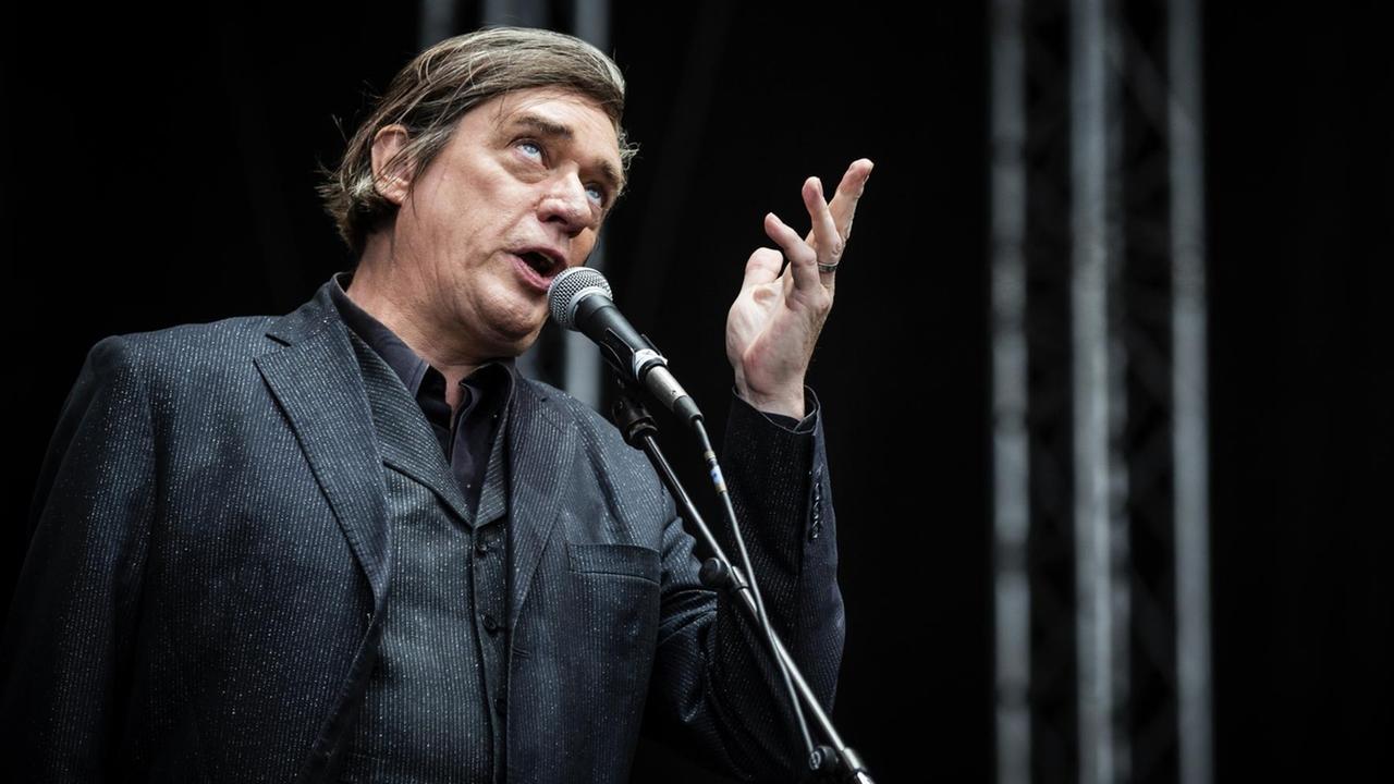 Blixa Bargeld steht in nachdenklicher Pose mit Blick nach oben am Mikro Blixa Bargeld steht in nachdenklicher Pose mit Blick nach oben am Mikro