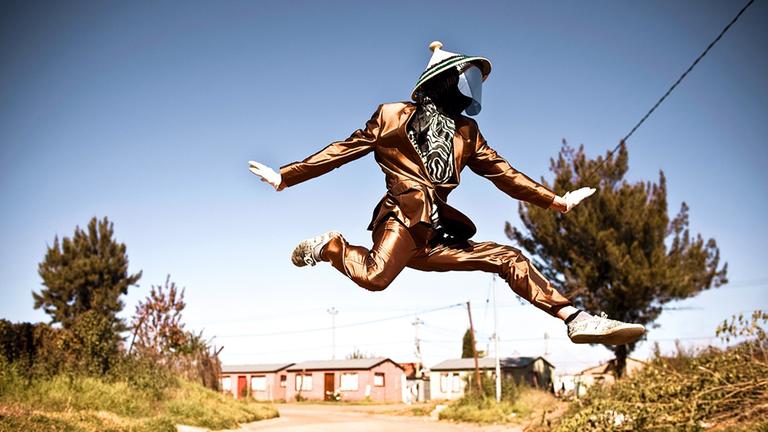 Ein Mann mit Maske springt über eine Straße