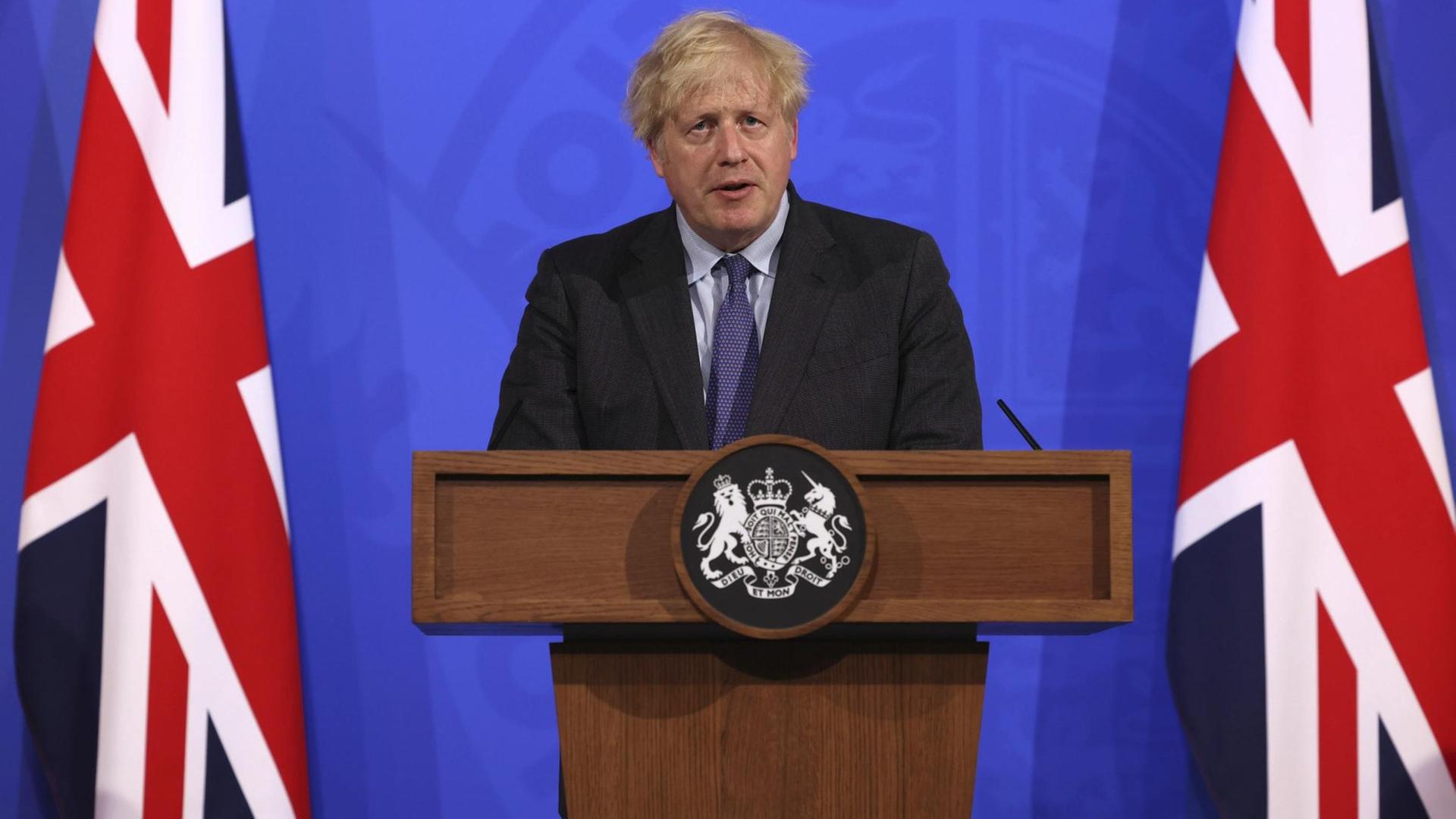 Großbritanniens Premier Boris Johnson steht neben Flaggen an einem Rednerpult. Großbritanniens Premier Boris Johnson steht neben Flaggen an einem Rednerpult.