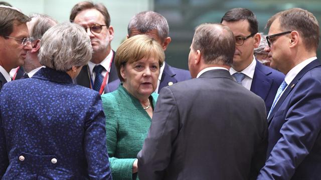 Bundeskanzlerin Angela Merkel (CDU) spricht mit anderen Staats- und Regierungschefs während eines EU-Gipfels.
