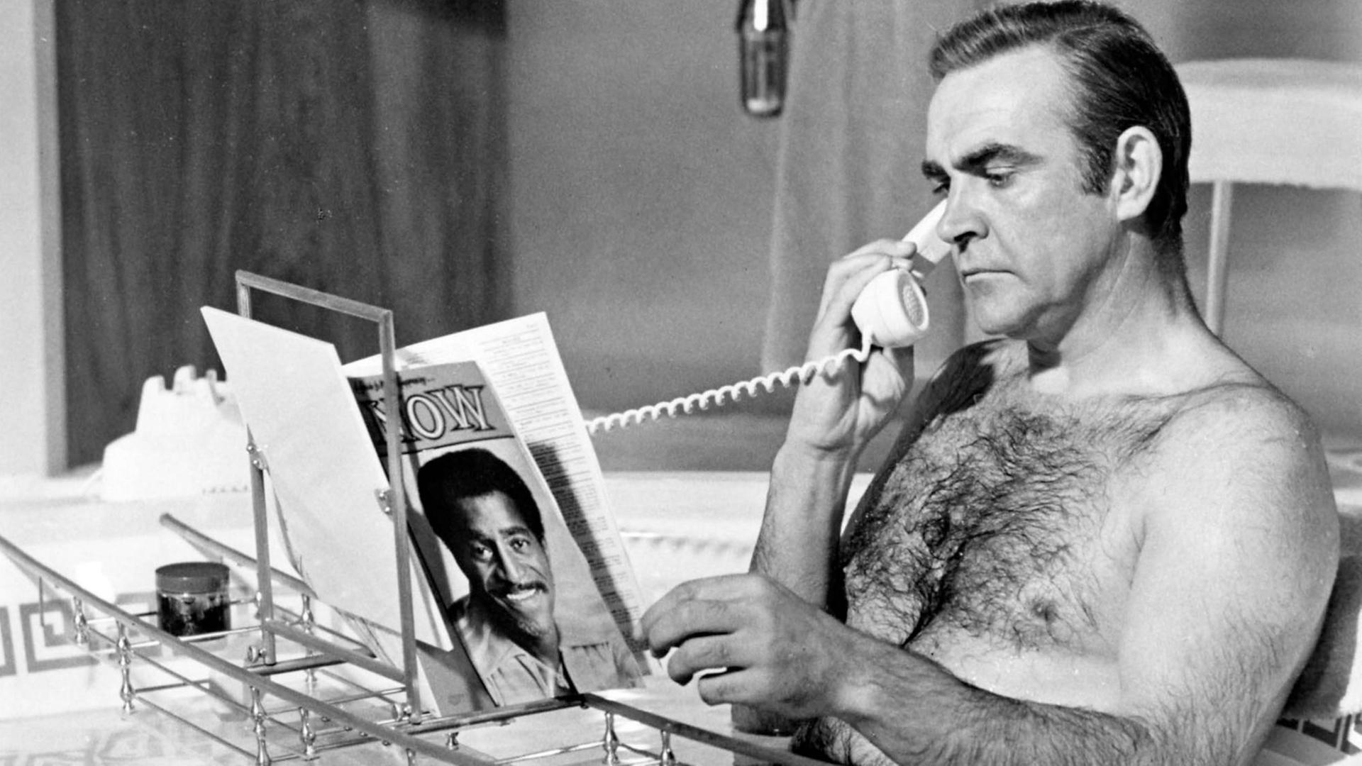 Sean Connery als James Bond in der Badewanne am Telefonieren und Zeitschrift durchblättern, Schwarz-Weiß-Foto Sean Connery als James Bond in der Badewanne am Telefonieren und Zeitschrift durchblättern, Schwarz-Weiß-Foto