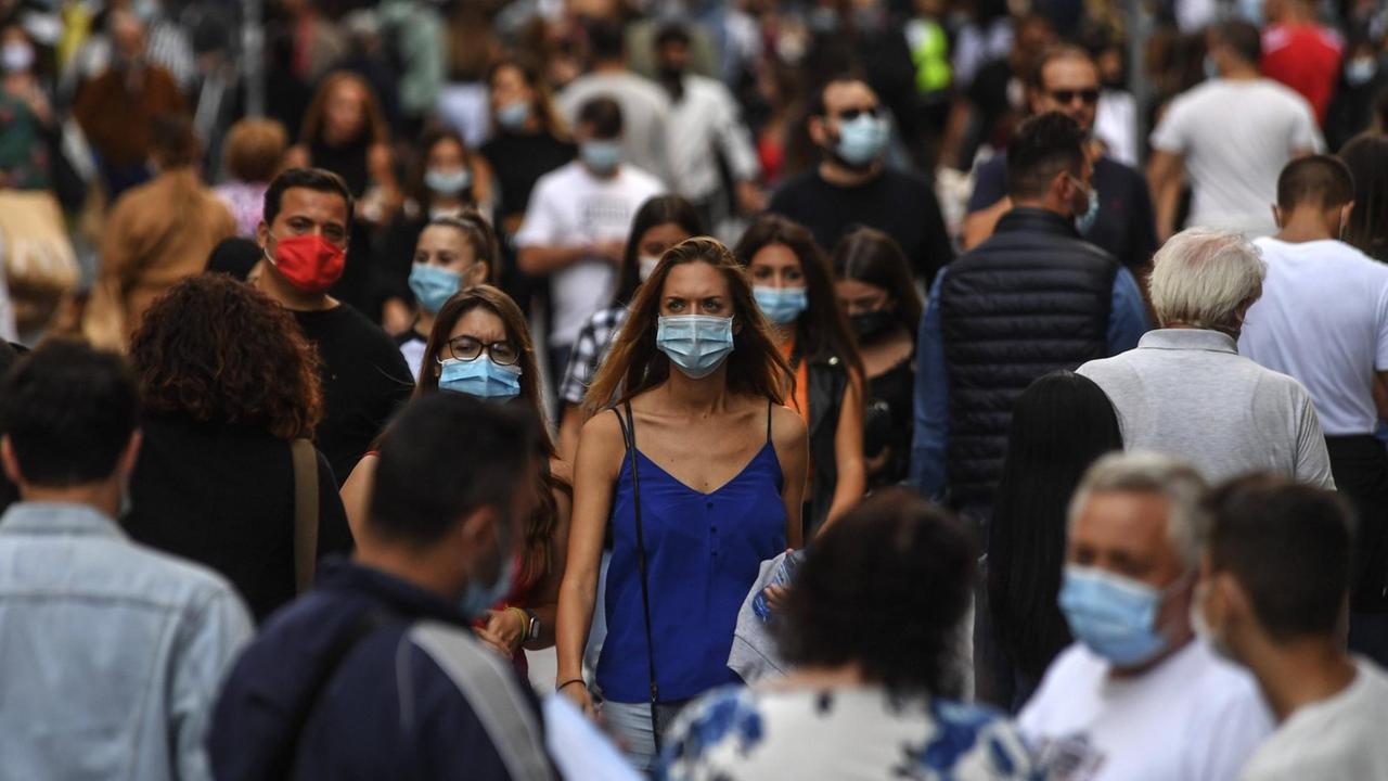Szene aus Süditalien: Menschen mit Mund-Nasen-Schutz laufen auf einer belebten Straße.