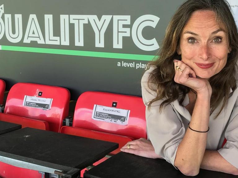 Karen Dobres sitzt im Stadion vor einem Plakat mit der Aufschrift "Equality FC".