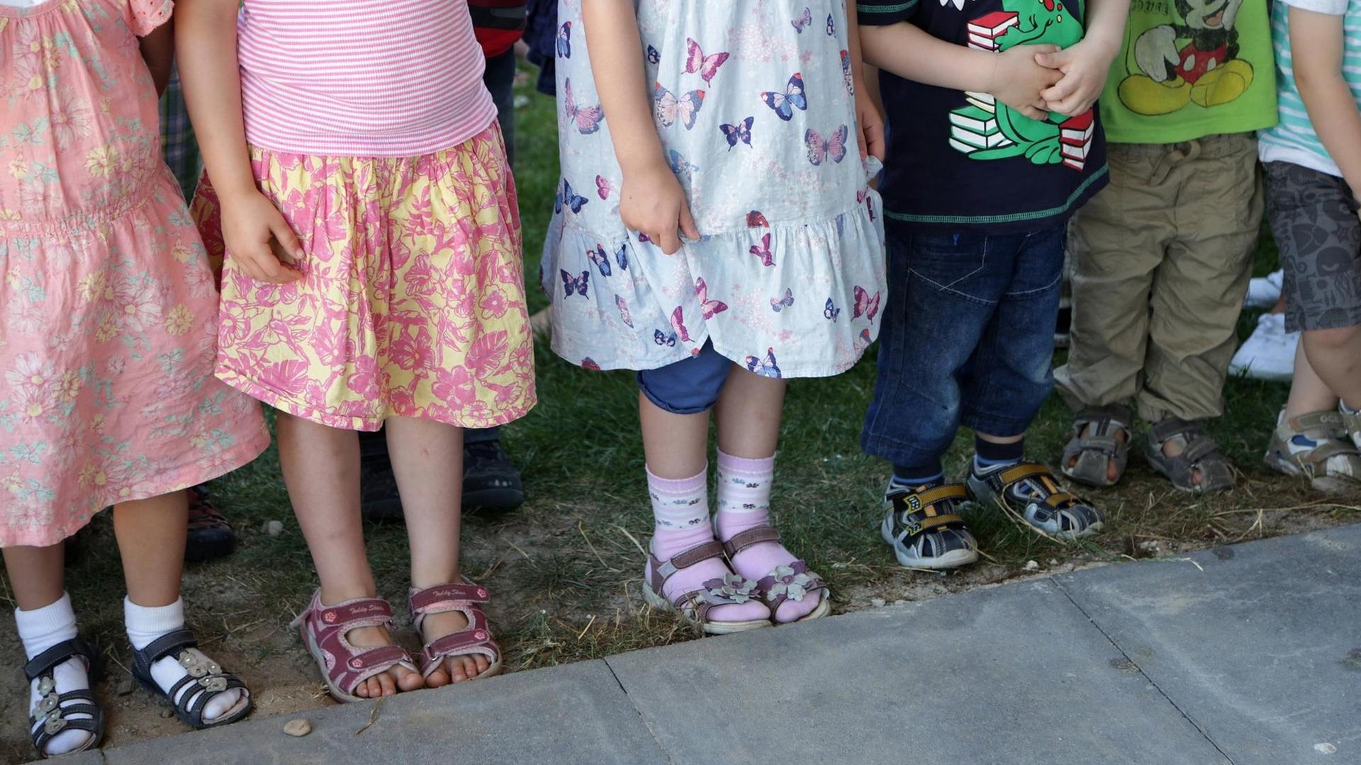 Symbolbild Kindertagesstätte: Füße und Beine von Kindern, die in einer Reihe stehen. Symbolbild Kindertagesstätte: Füße und Beine von Kindern, die in einer Reihe stehen.