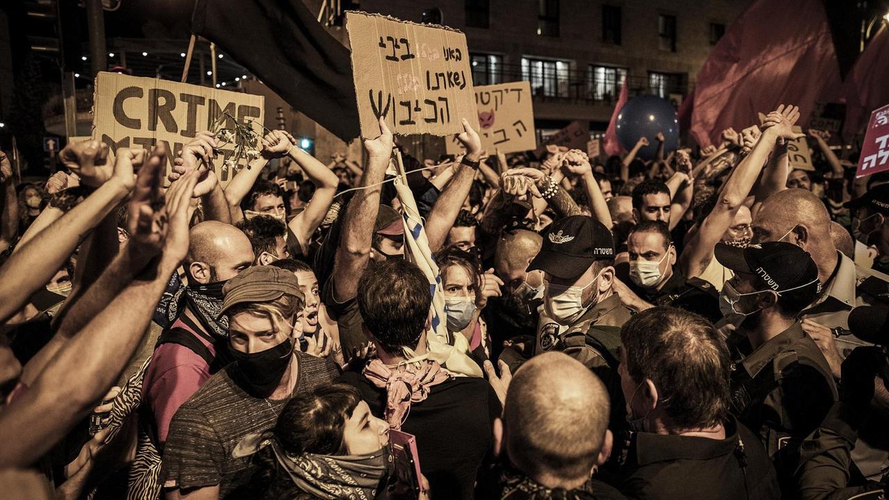 Demonstranten stehen mit Plakaten mit der Aufschrift "Crime" bei Protesten gegen den israelischen Ministerpräsidenten in der Nähe seiner offiziellen Residenz. Demonstranten stehen mit Plakaten mit der Aufschrift "Crime" bei Protesten gegen den israelischen Ministerpräsidenten in der Nähe seiner offiziellen Residenz.