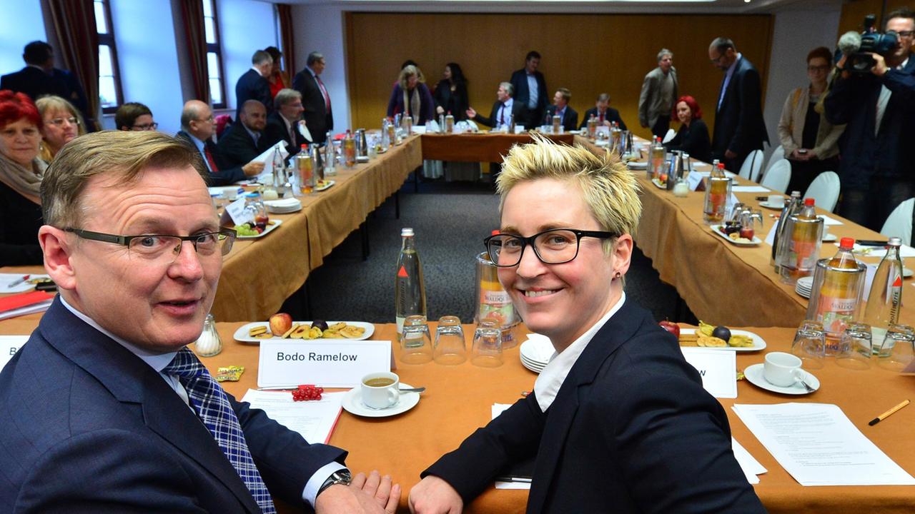 Linken-Fraktionschef Ramelow und die Linken-Landesvorsitzende Hennig-Wellsow sitzen am 05.11.2014 in Erfurt (Thüringen) am Verhandlungstisch zum Beginn der Koalitionsgespräche mit SPD und Grünen Linken-Fraktionschef Ramelow und die Linken-Landesvorsitzende Hennig-Wellsow sitzen am 05.11.2014 in Erfurt (Thüringen) am Verhandlungstisch zum Beginn der Koalitionsgespräche mit SPD und Grünen
