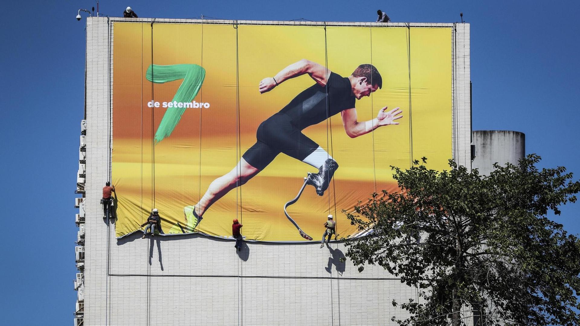 Arbeiter hängen in Brasilia ein Transparent in Vorbereitung auf die Paralympics auf