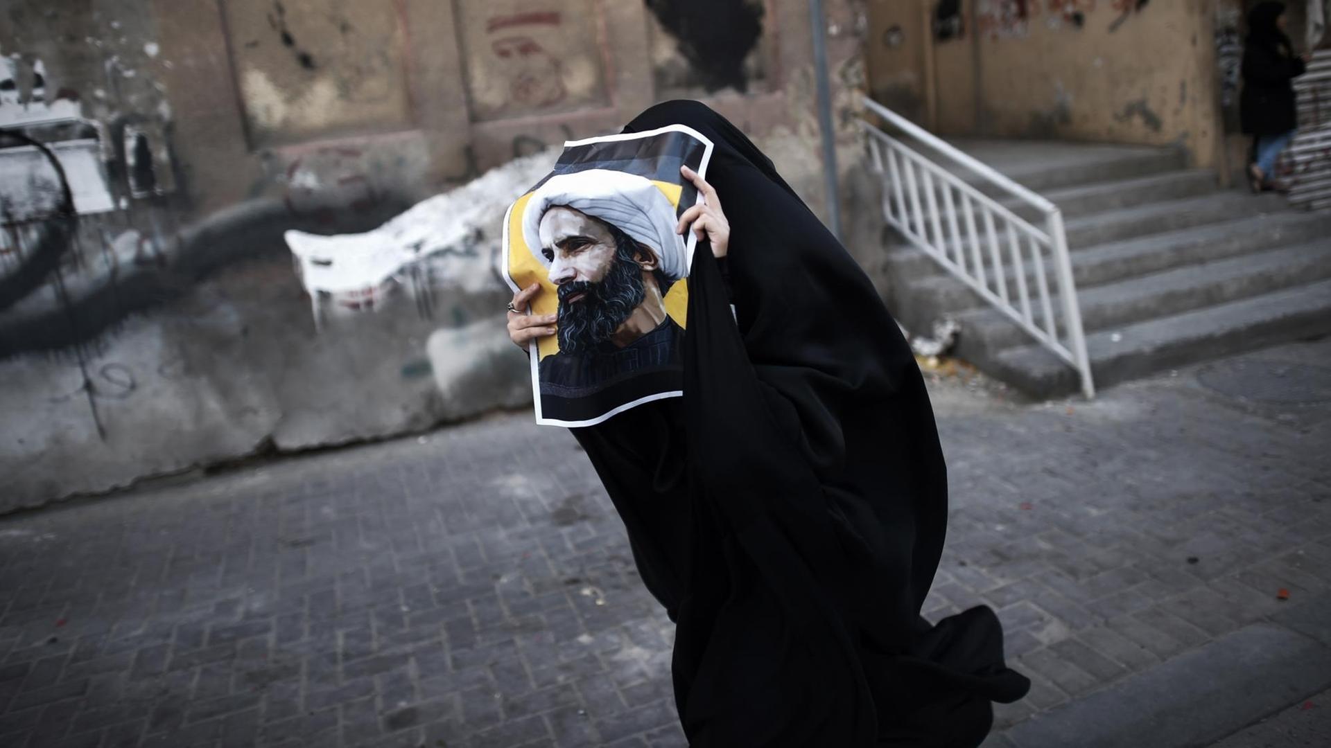 Eine Frau aus Bahrain hält ein Poster mit dem Foto des Schiiten Nimr al-Nimr während einer Protestkundgebung gegen seine Hinrichtung durch die saudi-arabische Regierung. Eine Frau aus Bahrain hält ein Poster mit dem Foto des Schiiten Nimr al-Nimr während einer Protestkundgebung gegen seine Hinrichtung durch die saudi-arabische Regierung.