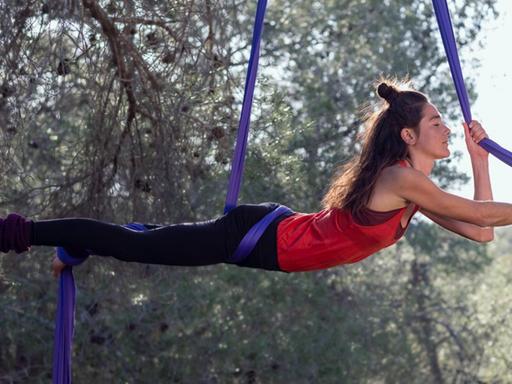 Eine junge Frau trainiert am Aerial Silk Tuch in der Natur. (Symbolfoto)