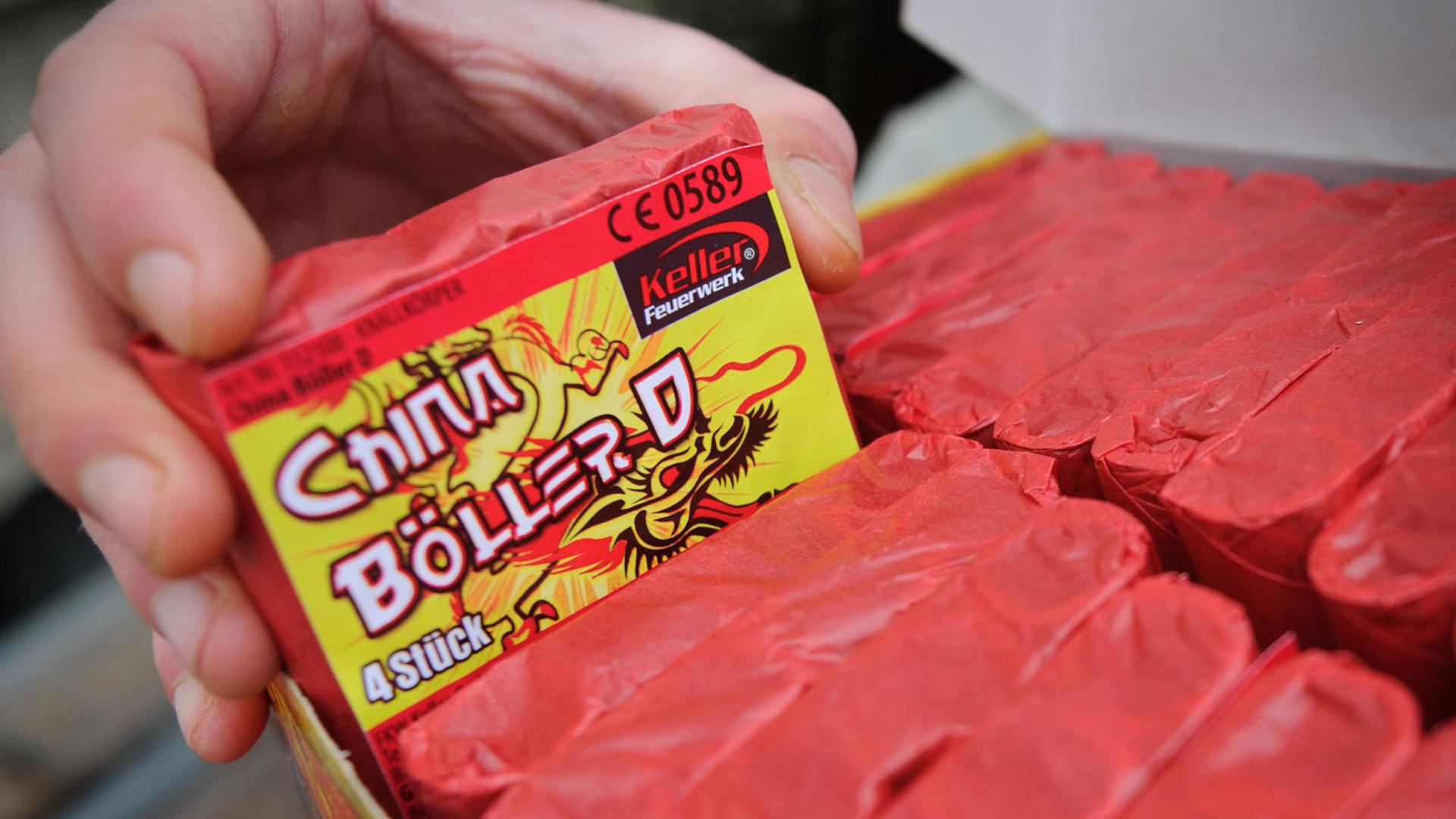Eine Hand nimmt eine Schachtel mit der Aufschrift "China-Böller" aus einem Karton. Eine Hand nimmt eine Schachtel mit der Aufschrift "China-Böller" aus einem Karton.